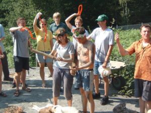 Gruppe Erwachsener im Freien, zwei halten Gegenstände, andere heben Bänder oder schauen zu.